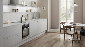 Single wall dove grey kitchen with copper knob handles, white grey marble kitchen worktop and built under oven.