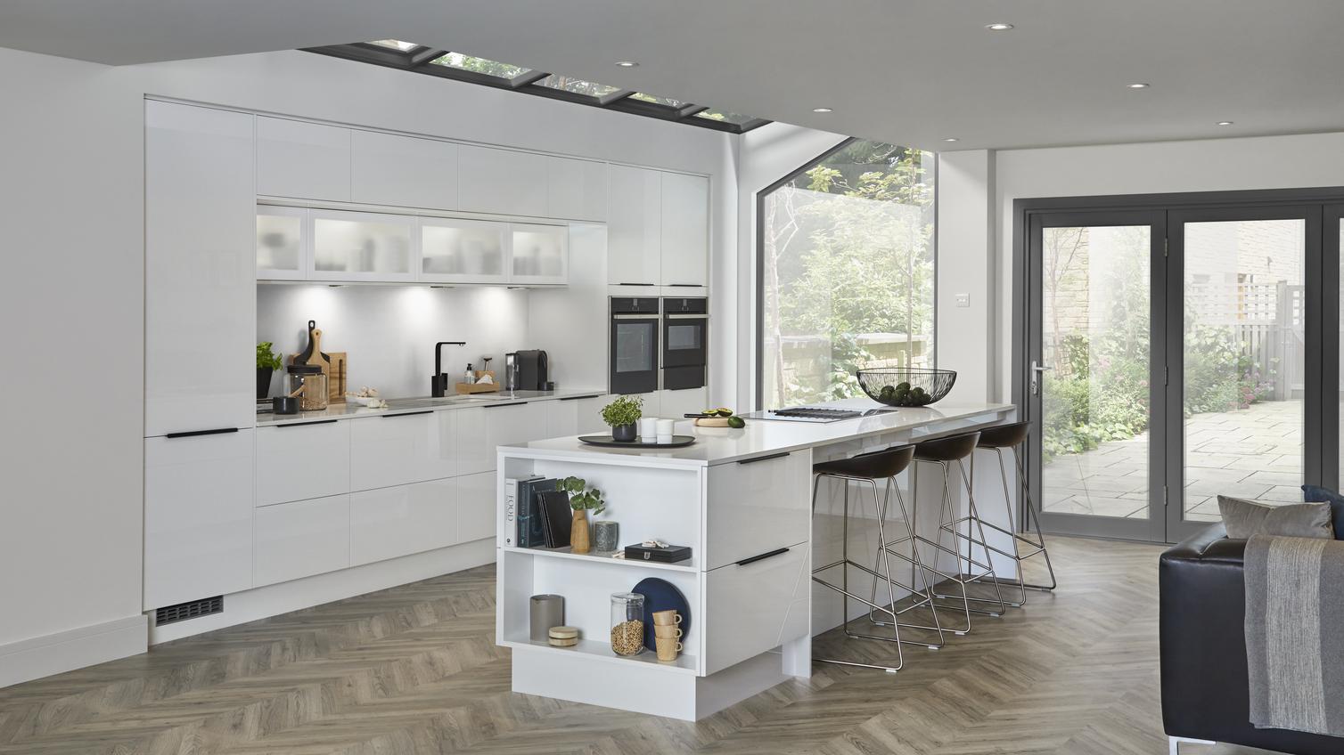 Modern white mirror gloss kitchen with two built in single oven and island unit with breakfast bar and open end shelving.