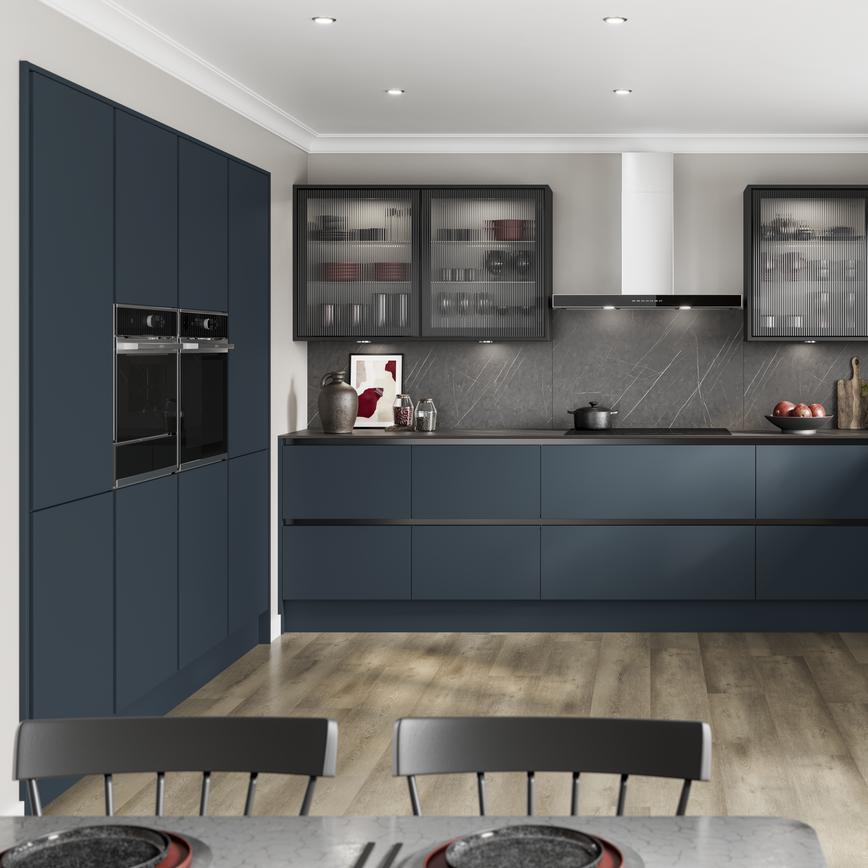 A marine blue handleless kitchen idea in a u-shaped layout. Has black profiles, fluted glass cupboards, and black worktops.