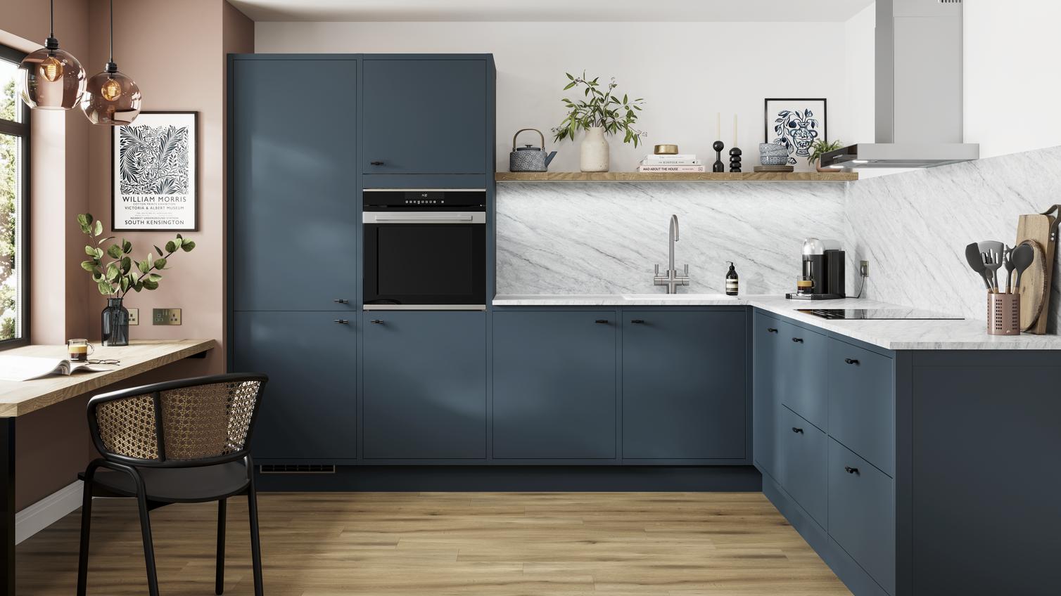 A marine blue In-Frame kitchen idea in an l-shaped layout, with black knob handles, white worktops, and oak laminate floors.
