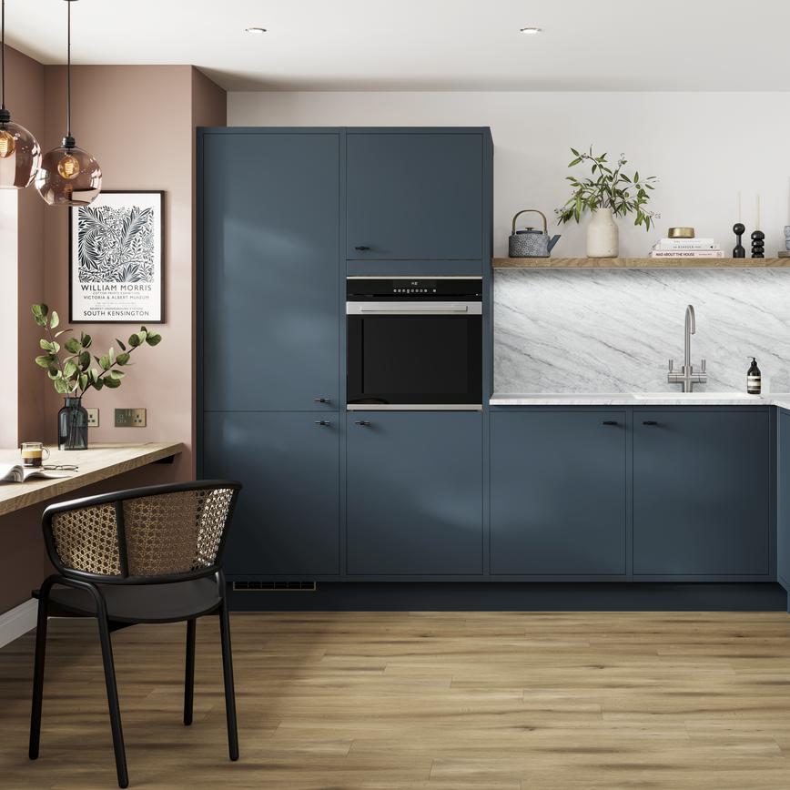 A marine blue In-Frame kitchen idea in an l-shaped layout, with black knob handles, white worktops, and oak laminate floors.