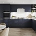 Contemporary blue kitchen idea with super-matt slab doors in a L-shaped layout. Has white marble worktops and brass handles.
