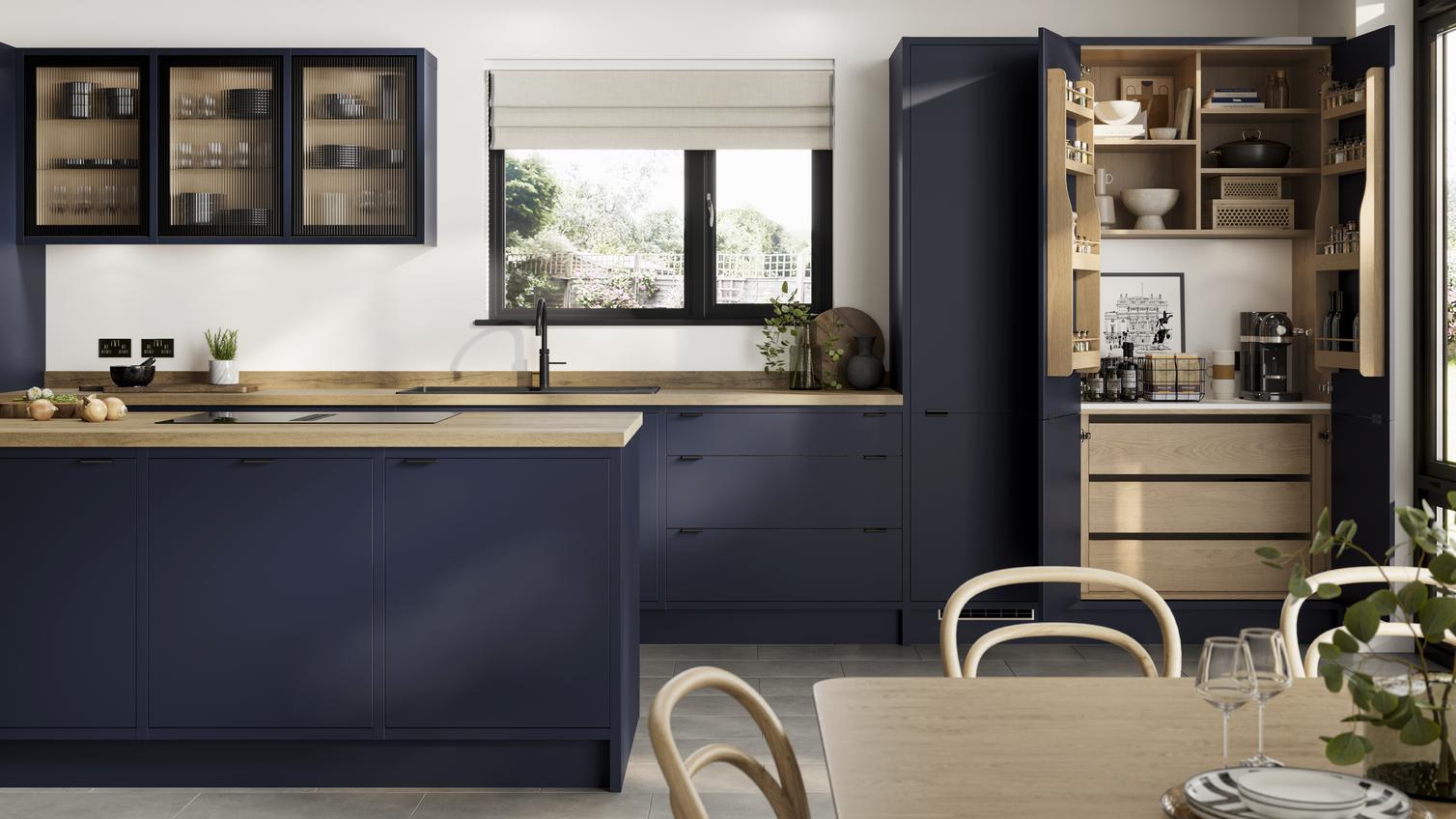 A contemporary blue kitchen with in-frame slab doors, white worktops, black handles, and glass units in an L-shape layout.