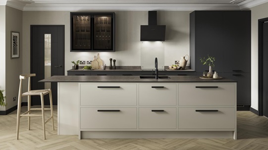 A charcoal and sandstone kitchen design with an island featuring an in-frame border, black bar handles, and a black tap.