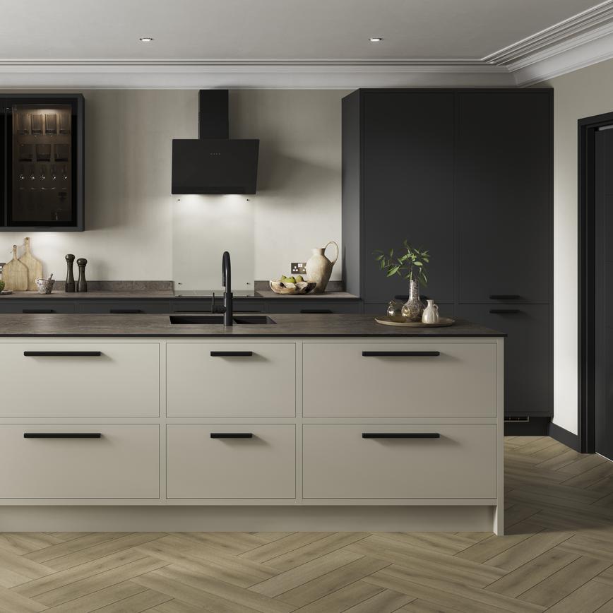 A charcoal and sandstone kitchen design with an island featuring an in-frame border, black bar handles, and a black tap.