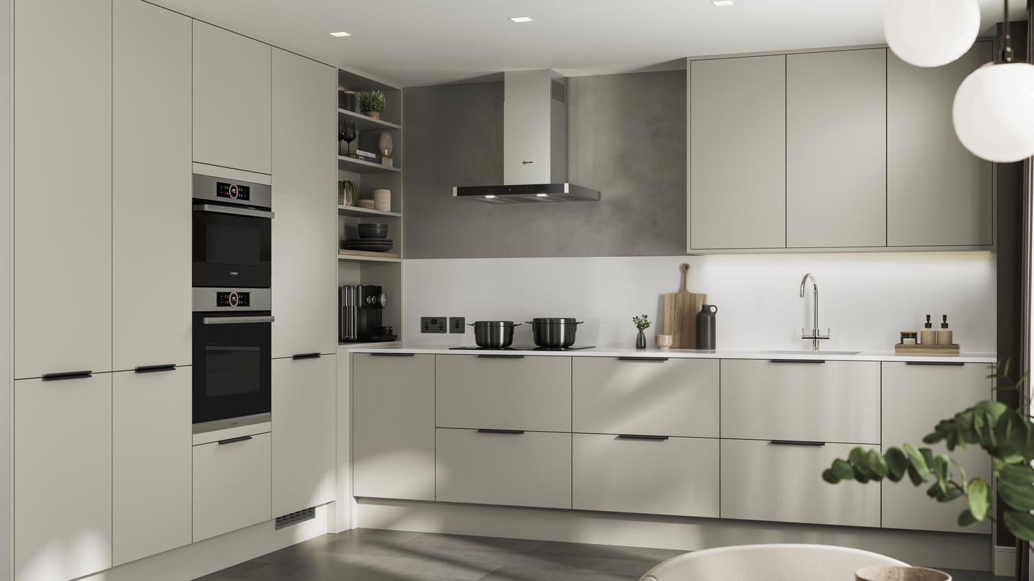 L-shape modern kitchen design with neutral slab cupboards in a matt finish. Includes two-drawer units and black bar handles.
