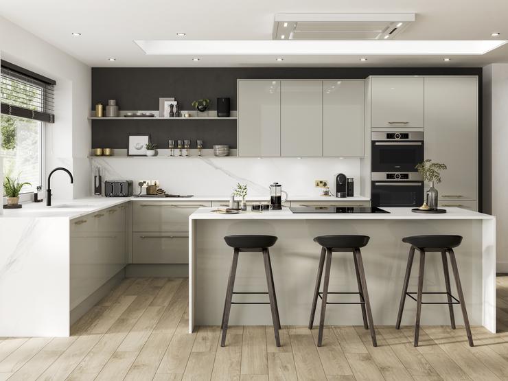 Contemporary kitchen in an island layout with neutral slab doors in a glossy finish. Contains white worktops and a black tap.