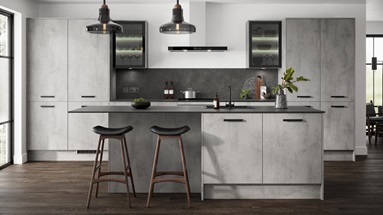 Grey kitchen in an island layout with concrete cupboard doors in a slab design. Includes black bar handles and glazed units.
