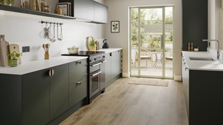 A dark green kitchen with matt cabinets, white countertops, range cooker, and warm oak-effect flooring.