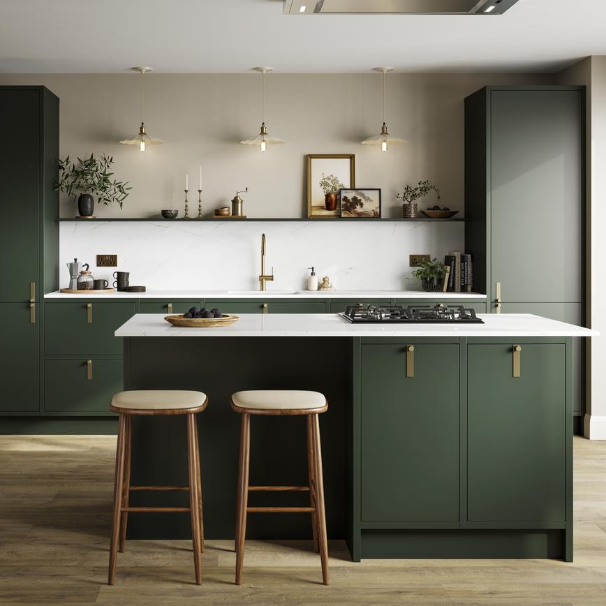 A dark green kitchen with matt cabinets, brass door handles, and a kitchen island complete with a gas hob.