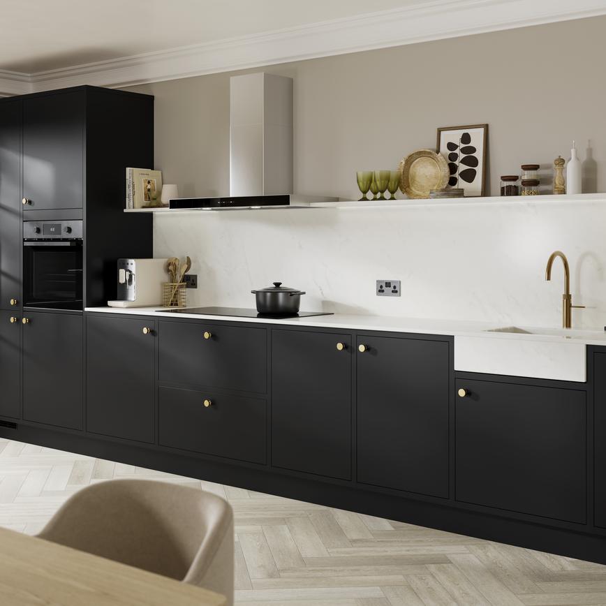 A one-wall kitchen with matt black cabinets and white worktops. Doors have brass handles and accessories.