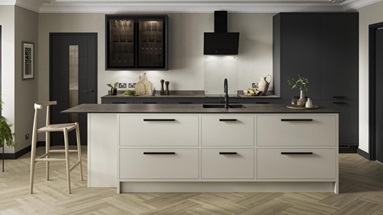 A charcoal and sandstone kitchen design with an island featuring an in-frame border, black bar handles, and a black tap.