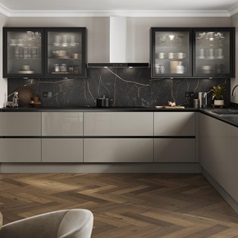 A handleless, l-shaped kitchen in a sand grey finish. There are fluted glass wall units and oak-style herringbone flooring.