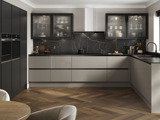 A handleless, l-shaped kitchen in a sand grey finish. There are fluted glass wall units and oak-style herringbone flooring.