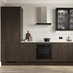 A handleless kitchen in a dark oak finish and single wall layout. There is oak flooring and a marble-effect splashback.