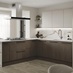 An l-shaped kitchen with cabinets in texted, walnut tones and white larder doors. It has marble worktops and backsplash.