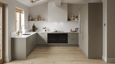 A sand grey, slab kitchen in a U-shaped layout. There are white worktops, plank flooring, and two large, black appliances.