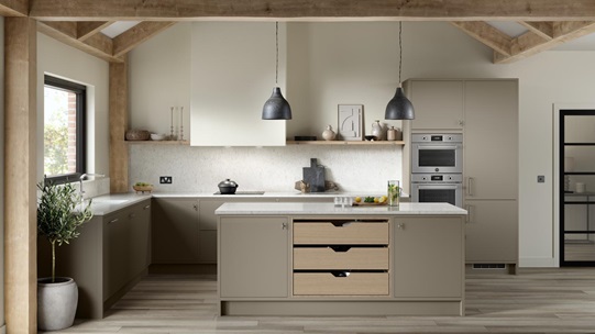 A sand grey, slab kichen with an L-shaped layout and in-frame design. It has white worktops and timber storage drawers.