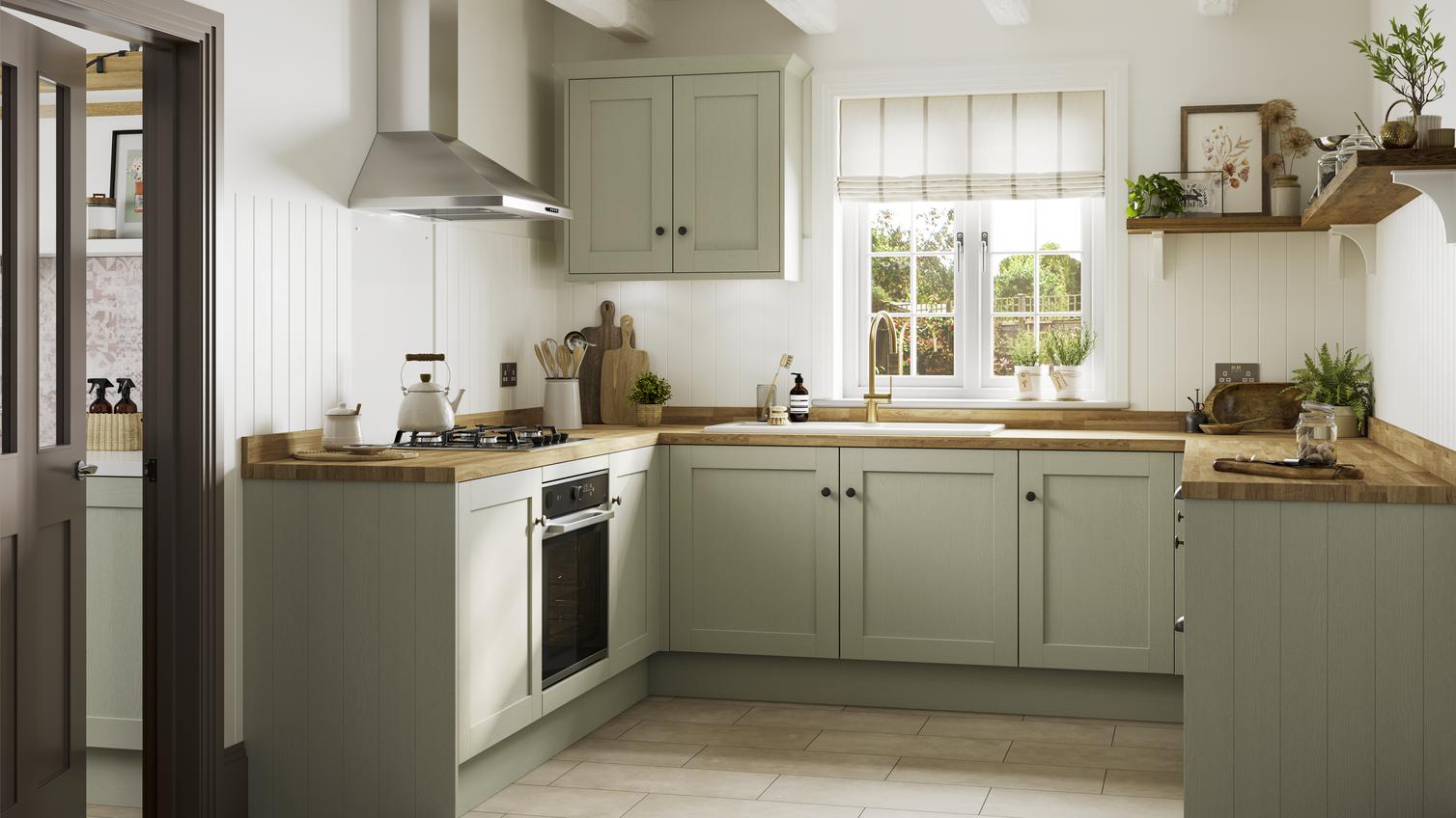 Sage green kitchen with shaker cabinet doors. It is in a u-shaped layout with a gas hob and timber-effect worktop