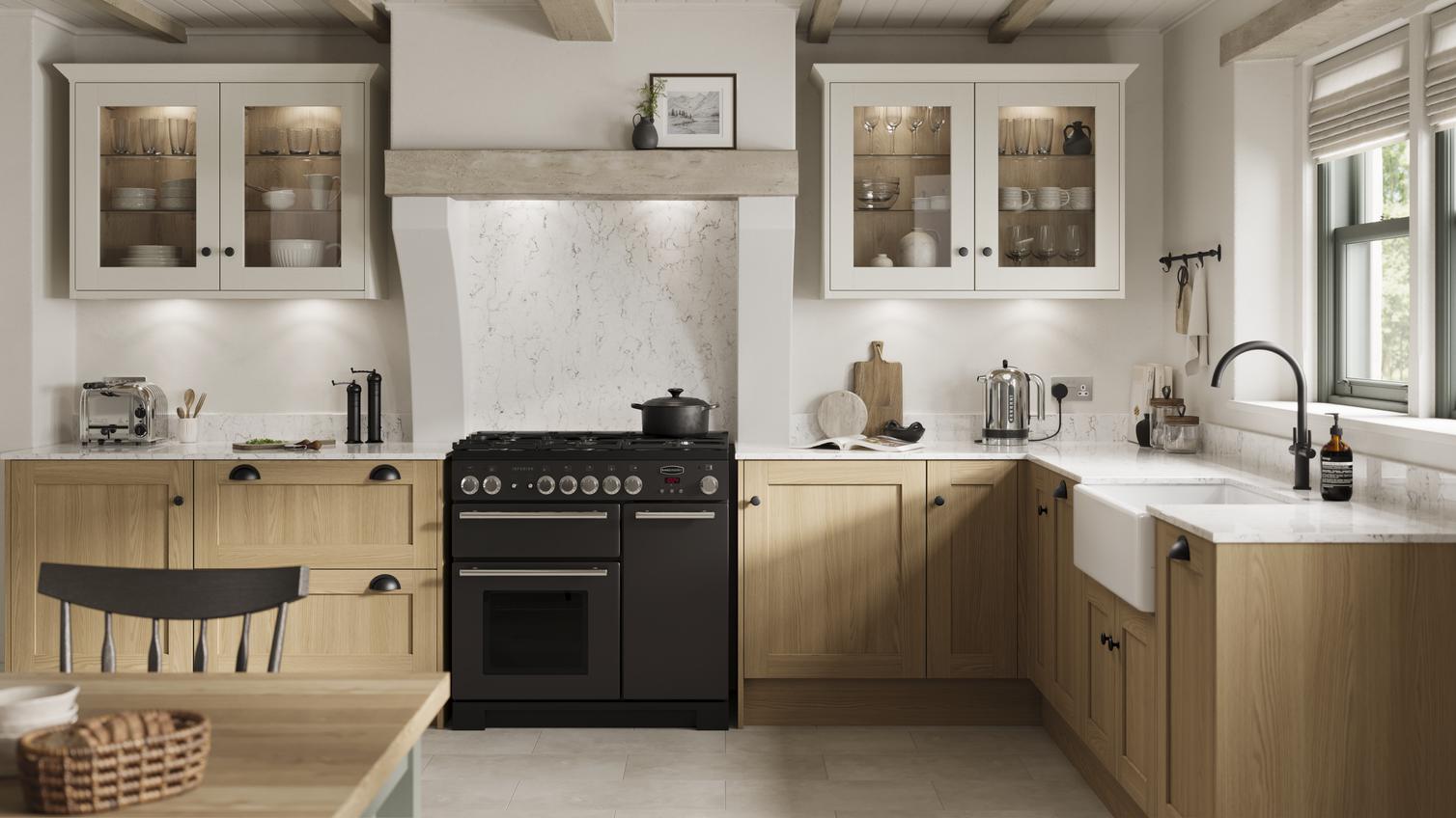 An L-shape kitchen with oak doors in a shaker style. Has white worktops and grey, tile-effect floors, and a black cooker.