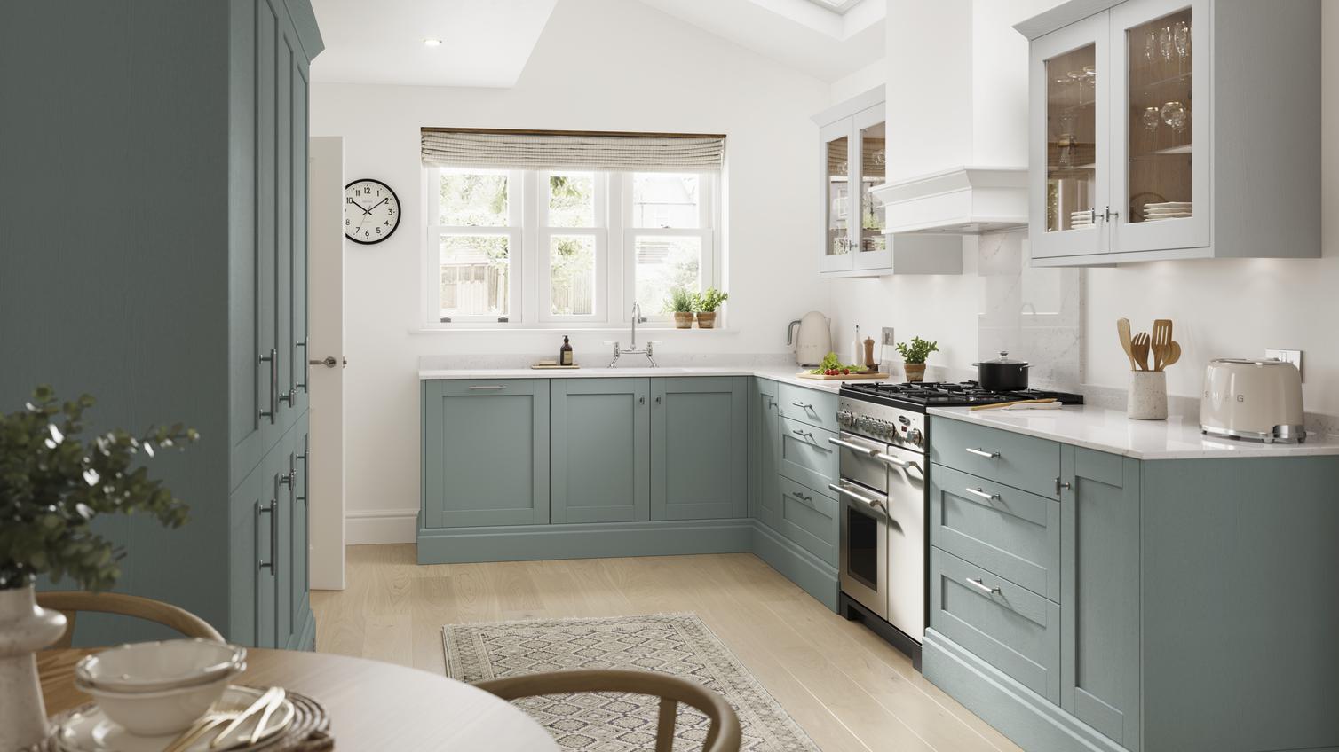 A blue kitchen idea with seafoam shaker cupboards. Contains white worktops, timber floors, and a double-bowl butler sink.