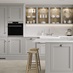 A dove grey shaker kitchen from Ilfracombe, in an island layout with breakfast bar. It has white counters and stone flooring