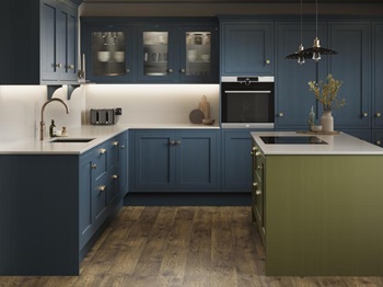A marine blue shaker kitchen from Ilfracombe, in an l-shaped layout. It has an olive-colour island and oak plank flooring.