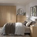 A bedroom with oak-fronted wardrobes, drawers, and dressers. The room has oak flooring and units have metallic rail handles.
