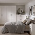 A gloss white bedroom set, featuring metallic d-handles. There is oak plank flooring and matching bedside tables.