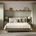 A Bridgemere bedroom with shaker wardrobes in a sage green tone. There is matching, painted wall panels & shelves above.