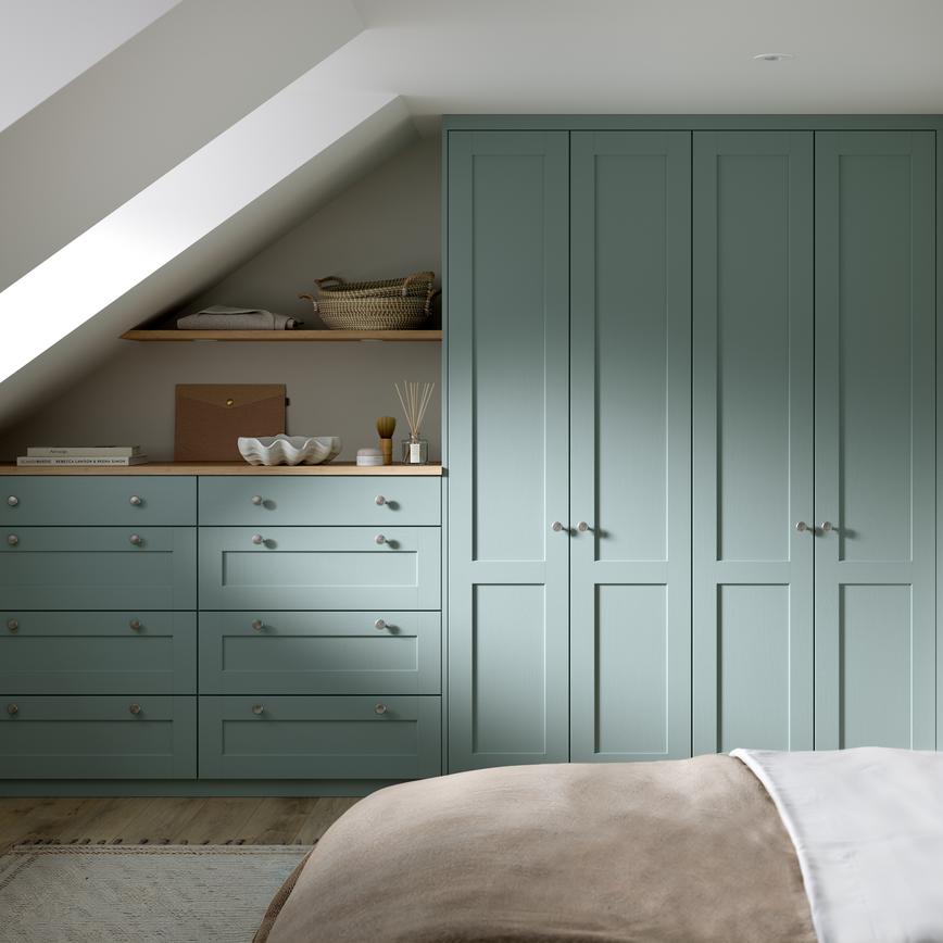 A Halesworth bedroom with seafoam blue wardrobes & drawers. It also has wood-effect flooring, and oak counters & shelving.