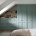 A Halesworth bedroom with seafoam blue wardrobes & drawers. It also has wood-effect flooring, and oak counters & shelving.