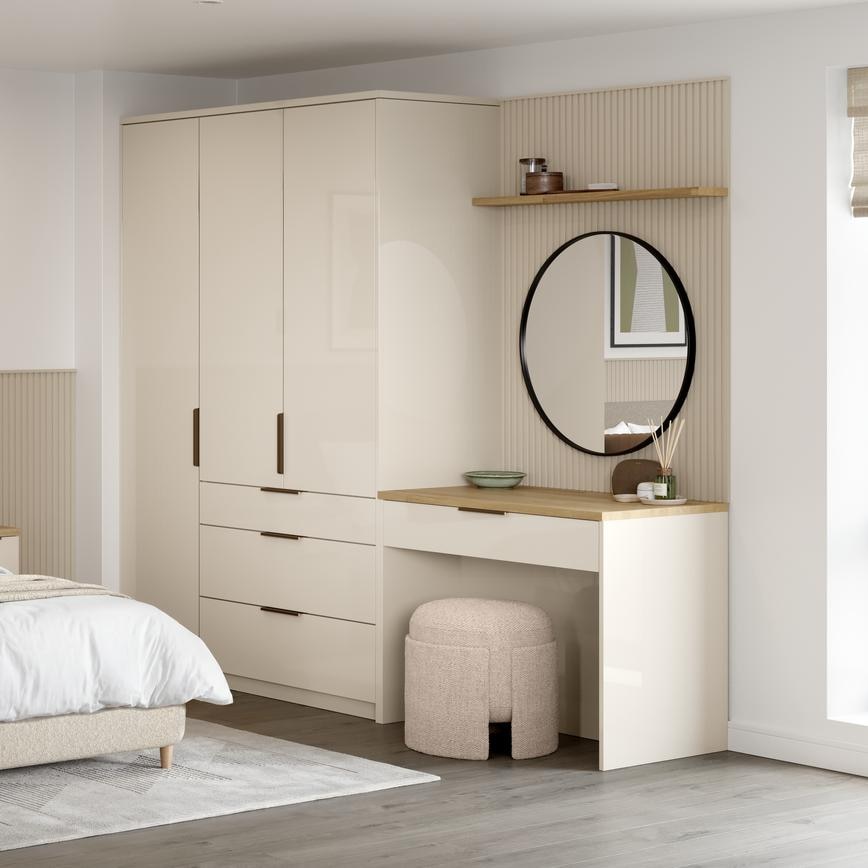 A large bedroom with sandstone cream wardrobe doors in a gloss finish. There is a matching vanity unit with rounded mirror.