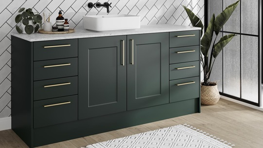 Compact green bathroom featuring shaker cupboards with a matt finish. Has brass handles, a white worktop, and an oak floor.