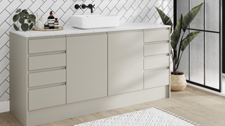 Modern integrated handle bathroom with matt sandstone cupboard doors, drawers, white worktop and tiles, and a black tap.