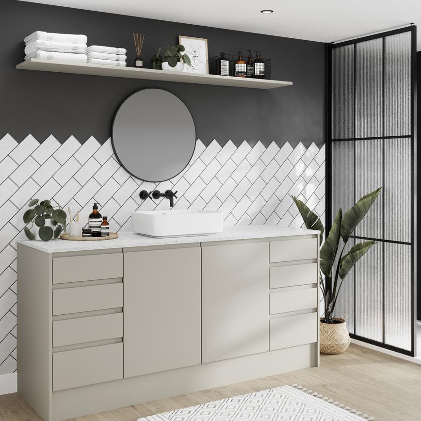 Modern integrated handle bathroom with matt sandstone cupboard doors, drawers, white worktop and tiles, and a black tap.