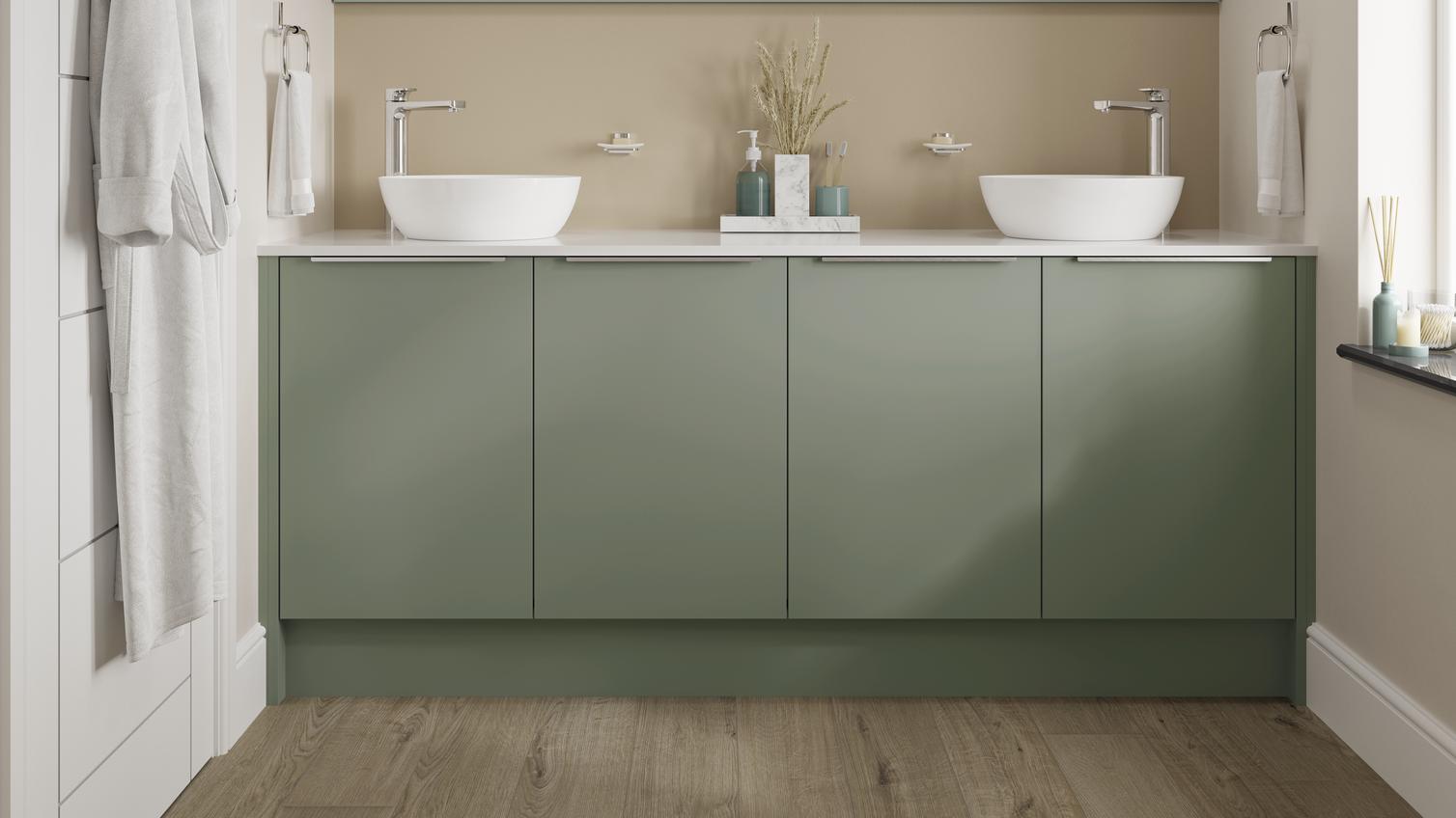 A small Greenwich bathroom with green cabinets, two sinks, and a large mirror. Bathroom features chrome taps and oak flooring.