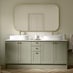 A pale green bathroom with a double sink vanity unit, featuring brass-effect handles. It also has vinyl herringbone flooring