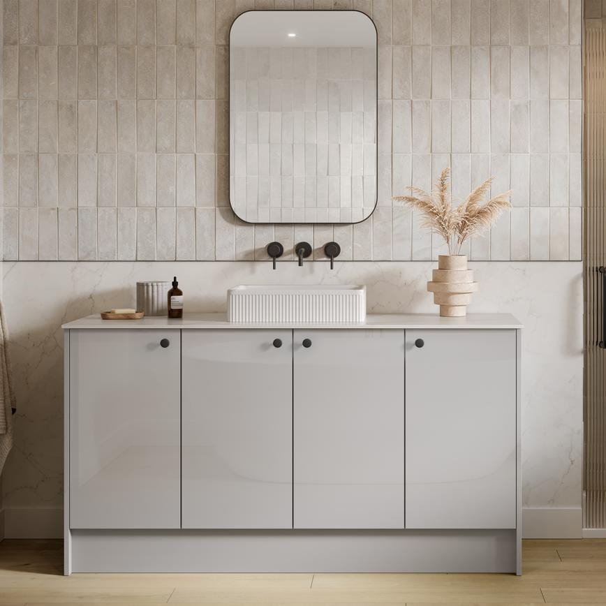 A gloss, dove grey bathroom with a single sink and black hardware. There is a glass shower door next to the vanity cabinets.