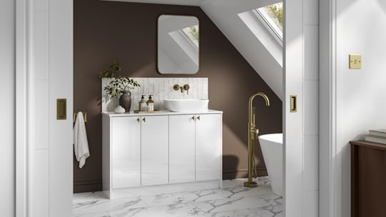 A small white bathroom with gloss cabinets and brass fittings. There is marble wall panelling and matching floors throughout