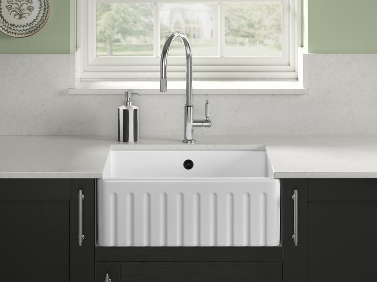 A fluted ceramic sink inside navy cabinetry