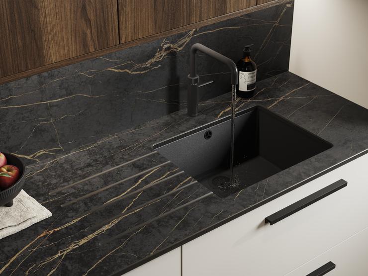 A dark, gold veined worktop made from stone, with a bespoke sink