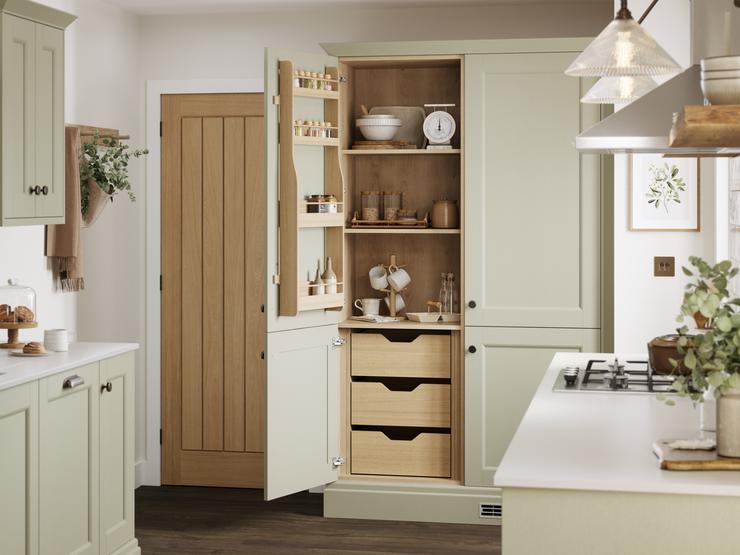 A sage green larder with shelving and storage drawers