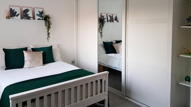 Bedroom with white sliding wardrobe doors with a mirror.