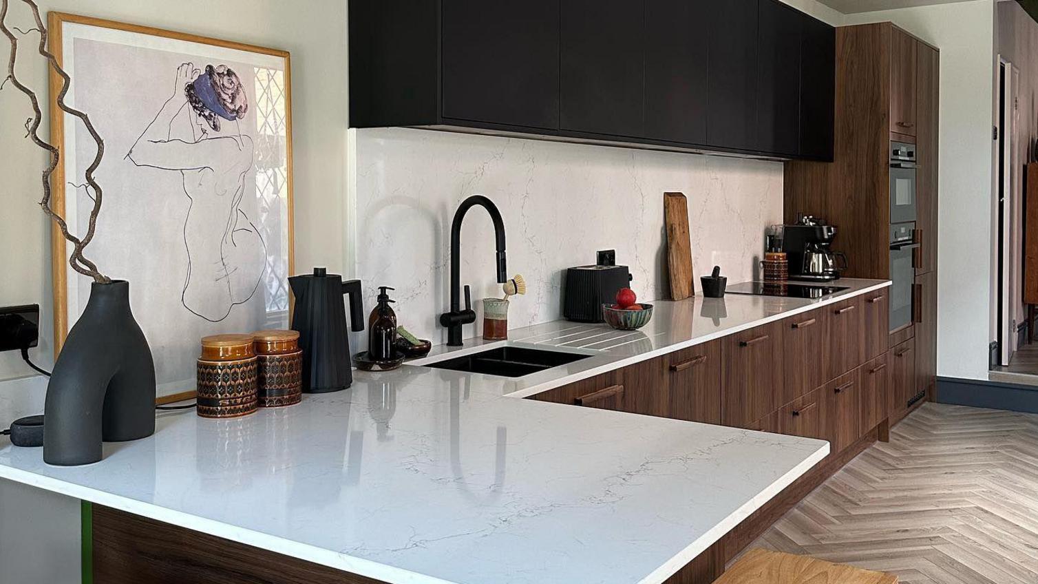 Mix and match kitchen idea featuring black and walnut units. Also includes a white worktop, a black sink, and chevron floors.