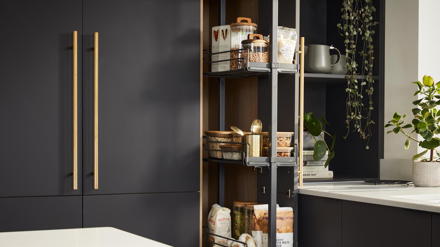 Howdens 2022 Kitchen Of The Year Winner's kitchen with pull-out pantry, black slab doors and brass handles for an opulent look.