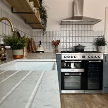 White quartz worktop with a white ceramic sink, dusk blue cabinet doors, and a range cooker and extractor fan.