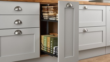 A pull-out storage solution with shelves full of dried goods