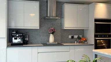 White single wall kitchen idea with integrated handle cupboards, a grey worktop, induction hob and integrated appliances.