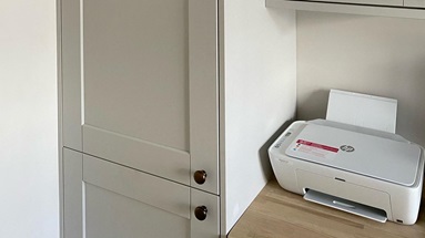 Grey shaker home office idea with long larder style unit, wall unit, black knob handles, and an oak work surface as a desk.